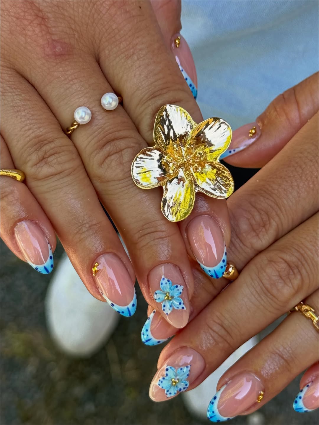 Floral French tip nails with blue accents, creative and detailed.