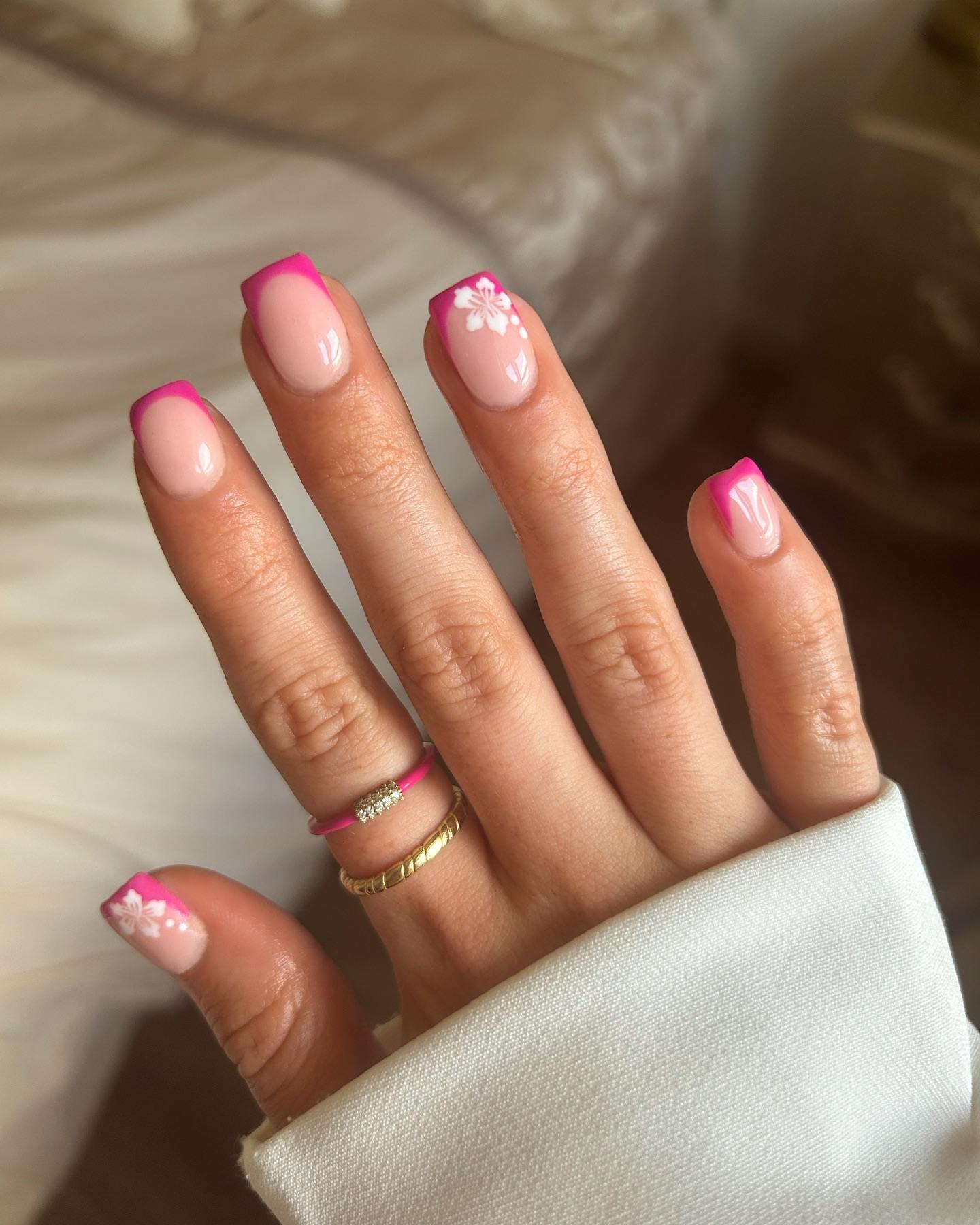 Square pink French tips with floral accent.