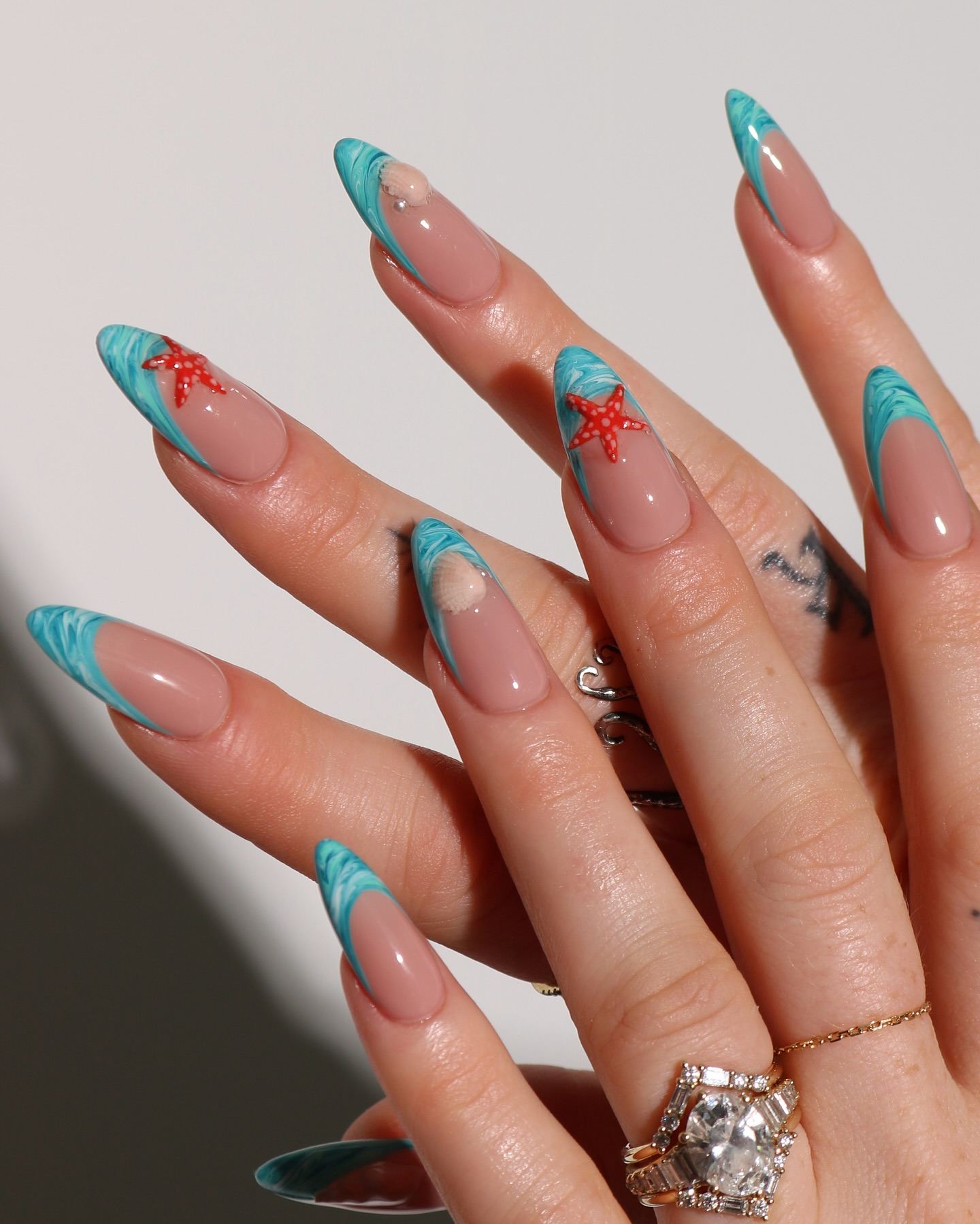 Stiletto turquoise ocean-themed French tip nails.