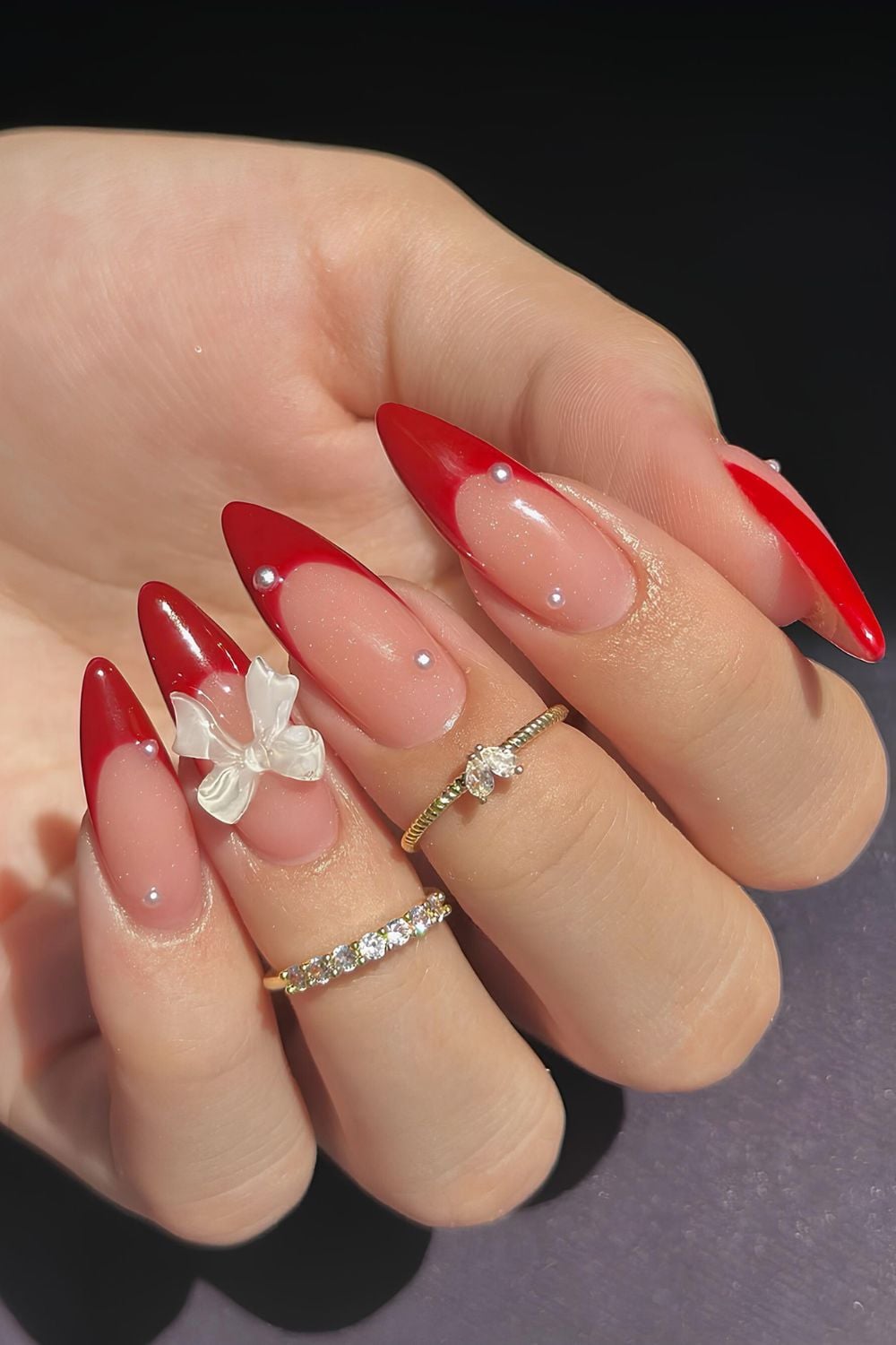 Red French tips with pearl accents and 3D bow.