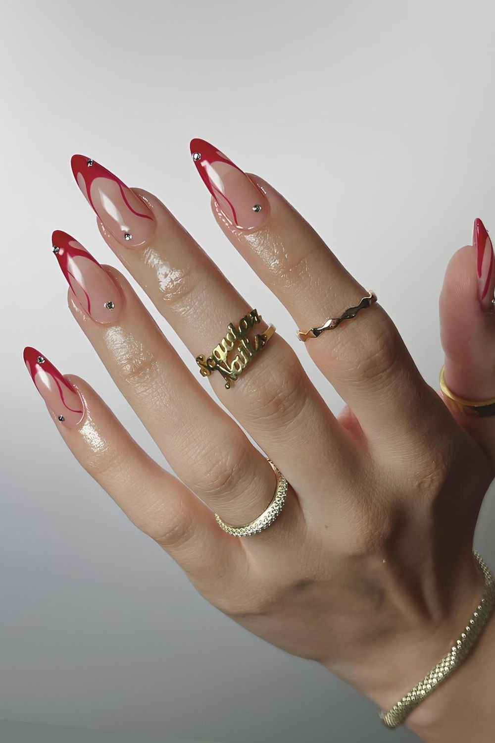 Swirled red tips on almond nails, artistic and bold.