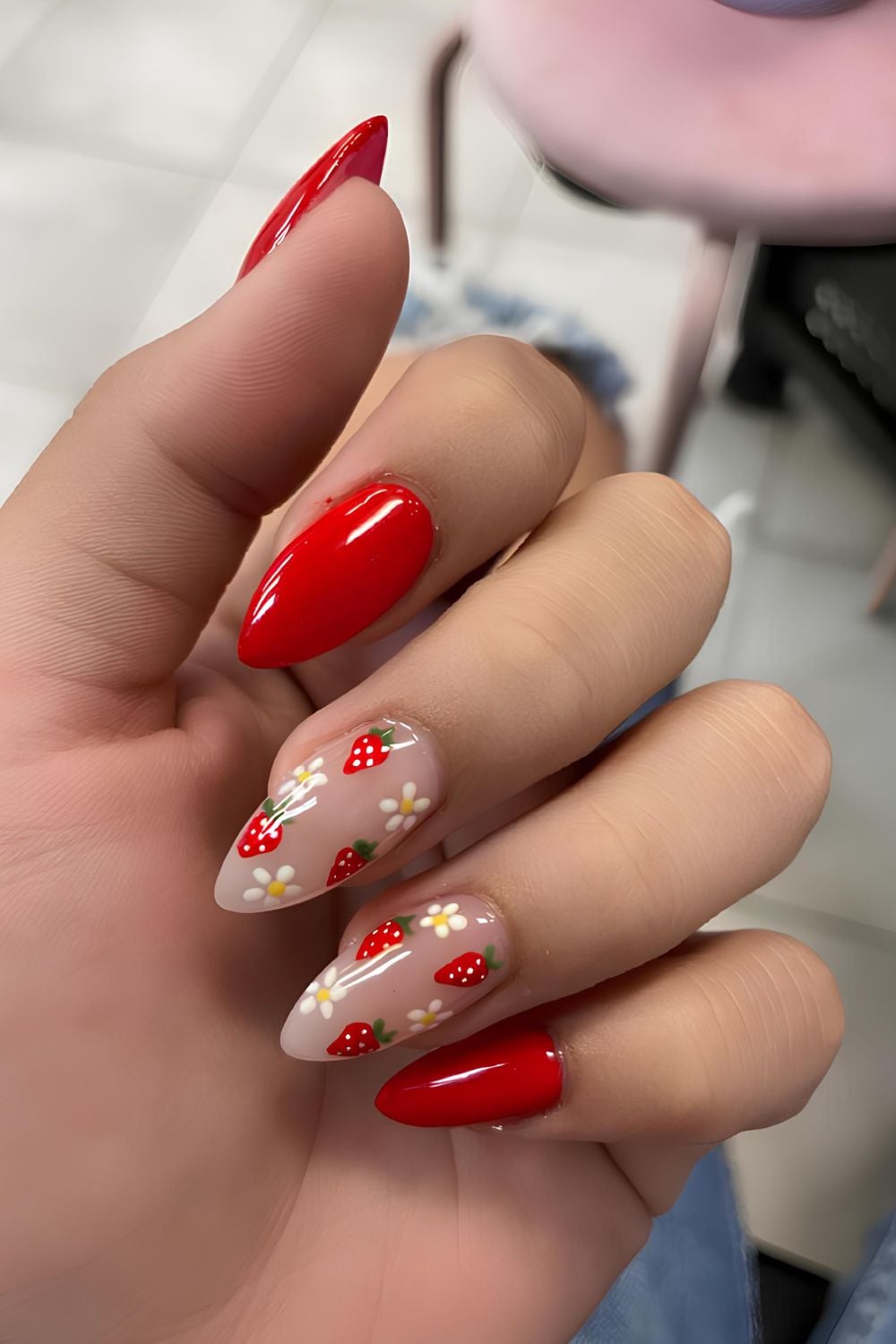 Red nails with strawberry and daisy accents, playful and fun.