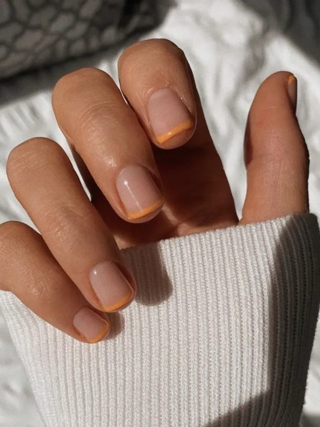 Short nude nails with orange French tips
