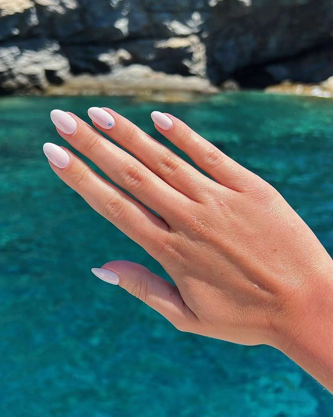 Soft pink nails against a sea backdrop