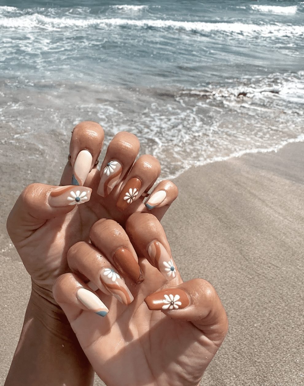 Neutral nails with daisy accents on beach