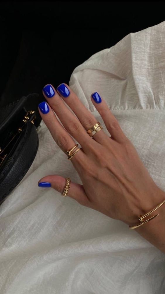 Blue flower nails with blue cateye nails, purple chrome nails, and gold orange and accents