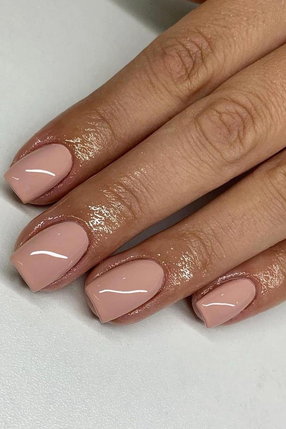 Nude almond nails with gold accent, featuring milky nail art and simple ombre for summer on short dark skin.