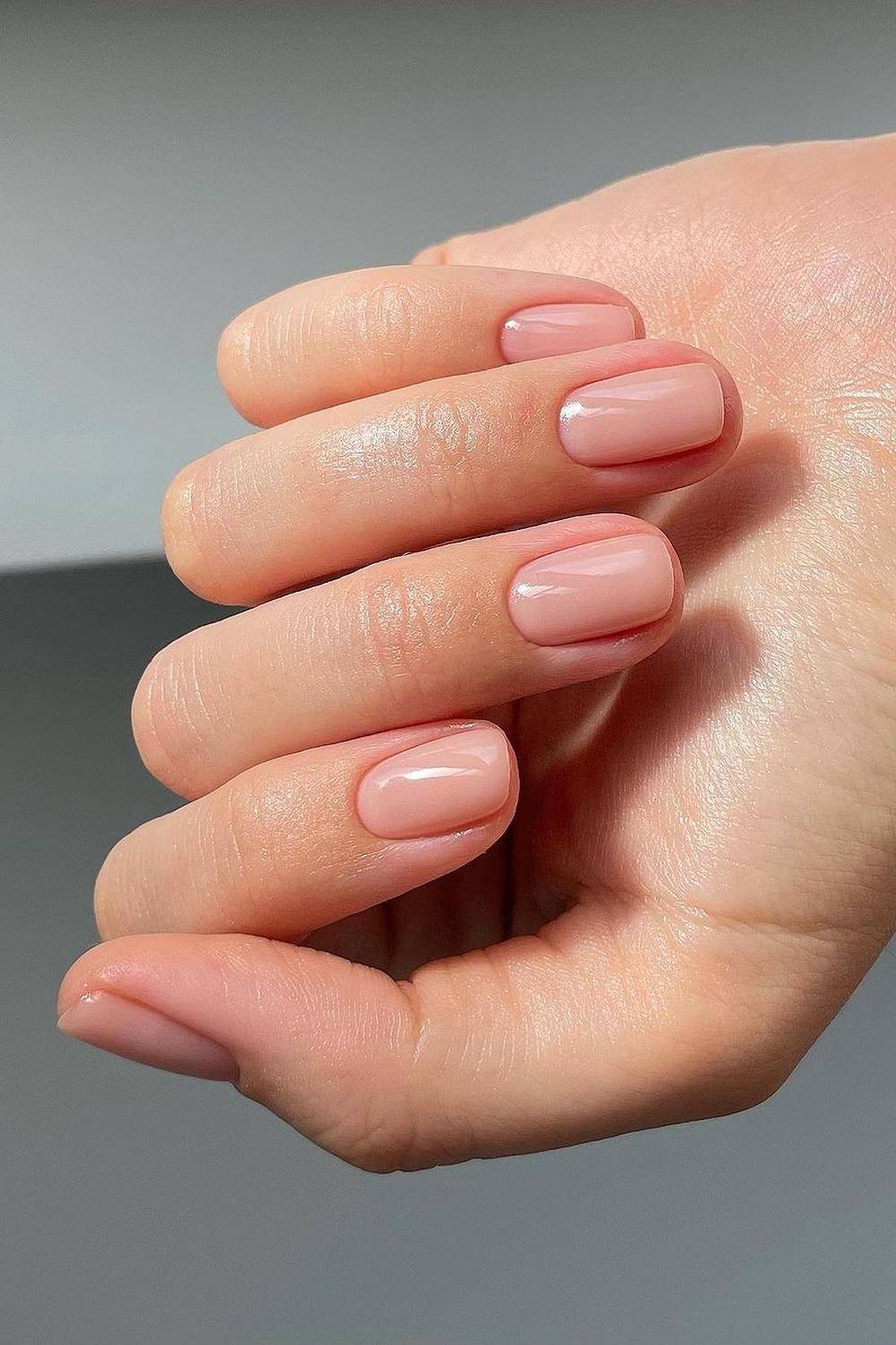 Nude french nails on short dark skin with simple almond chrome and gold accent.