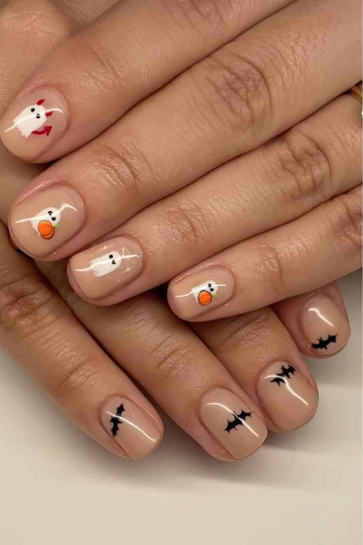 Nude nails with cartoon ghost and pumpkin designs