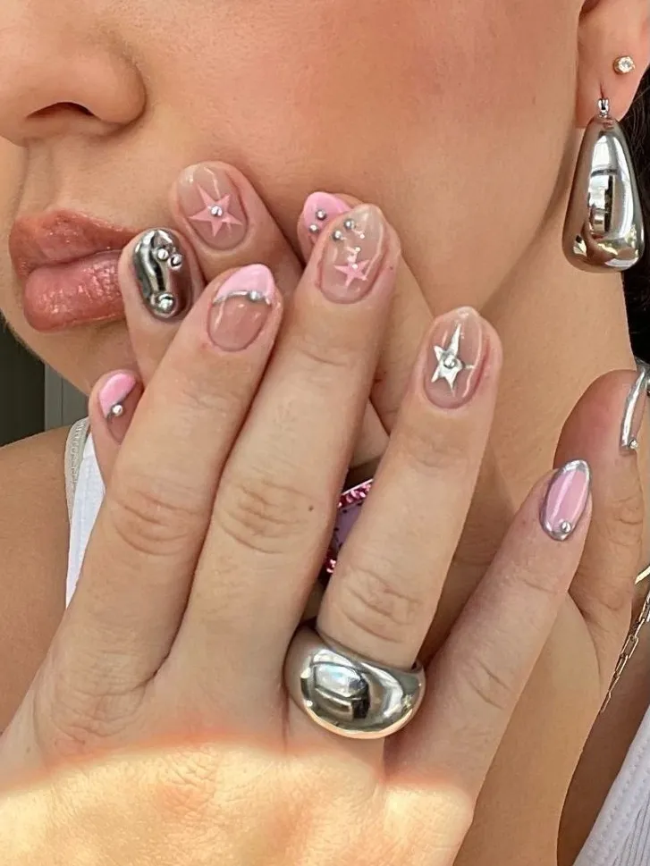 Y2K pink nails with chrome accents and stars.