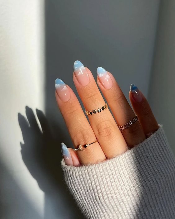 Almond nails with blue cloud tips.