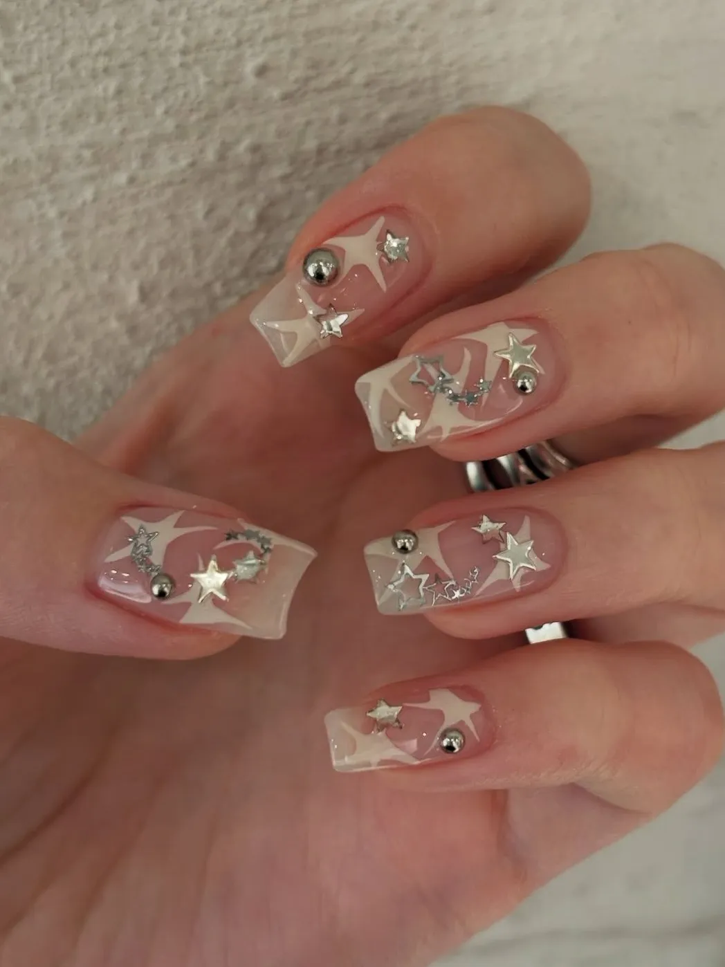 Square nails with starry accents on nude base.
