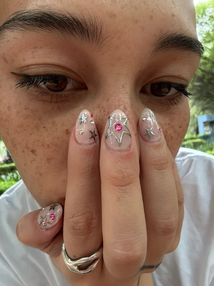 Clear nails with stars and pink accents.