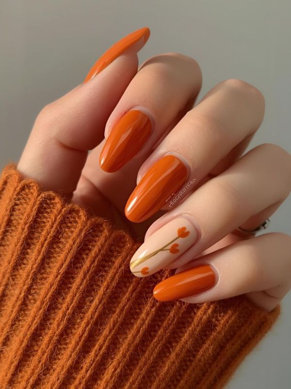 Orange nails with leaf accents, fall season nail art