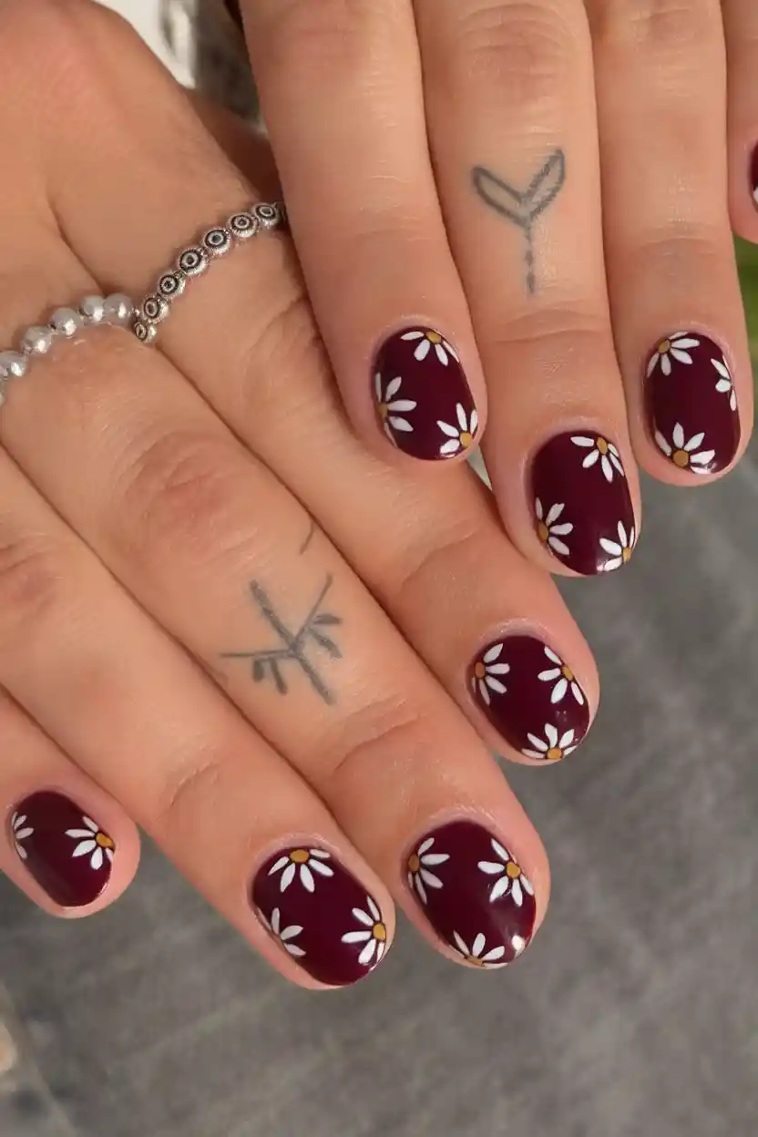 Burgundy nails with daisy floral accent, playful nail art