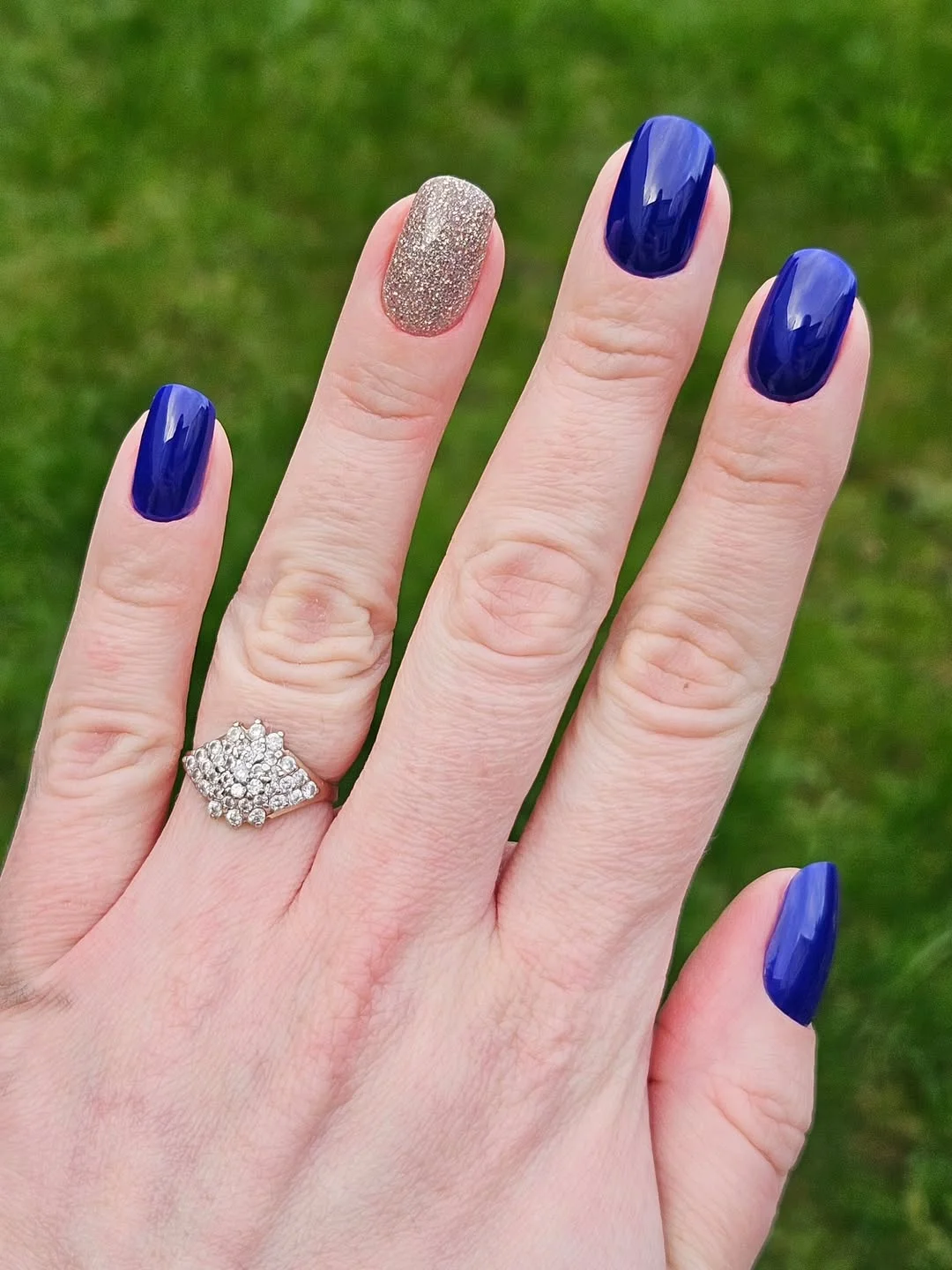 Short oval nails with blue polish and glitter accent nail