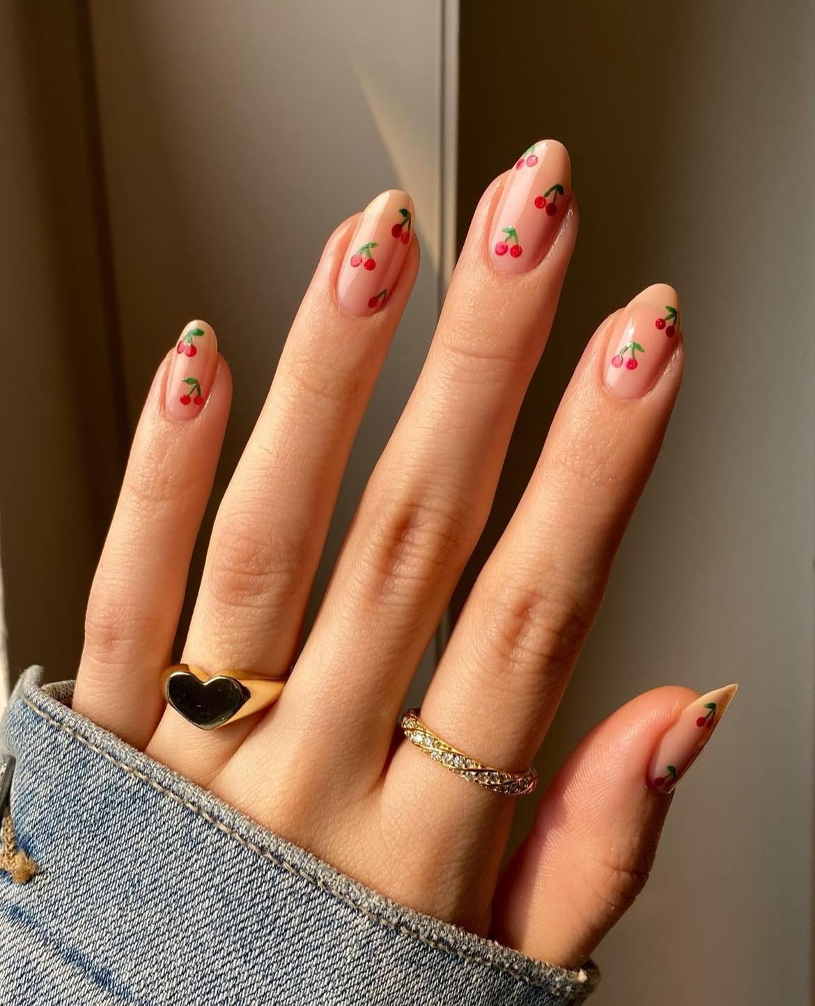 Almond nails with nude polish and cherry art