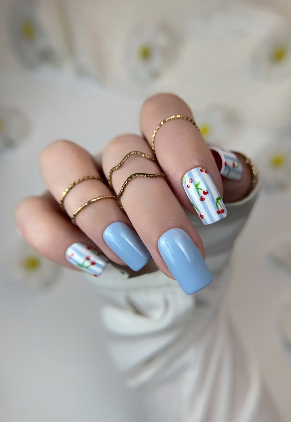 Square nails with blue polish and cherry art