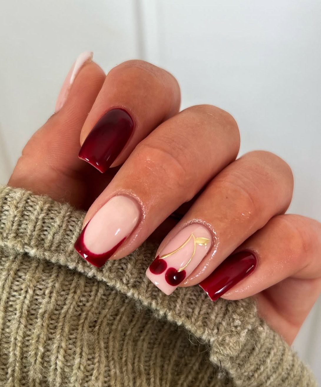 Square nails with red French tips and cherry accents