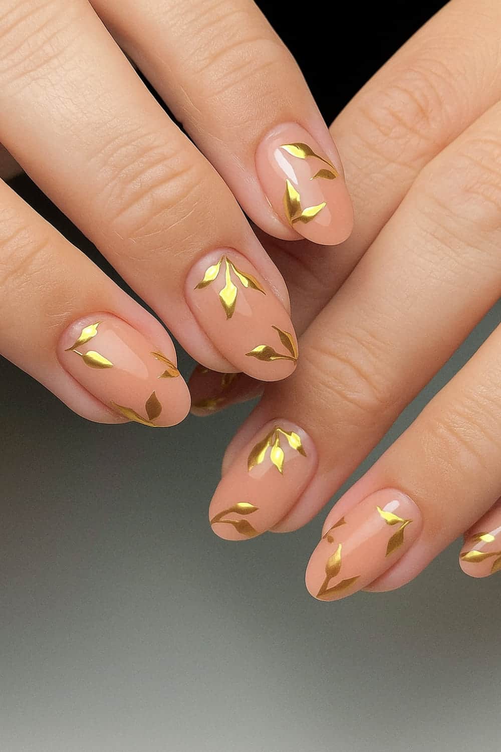 Golden leaf accents on almond nails.