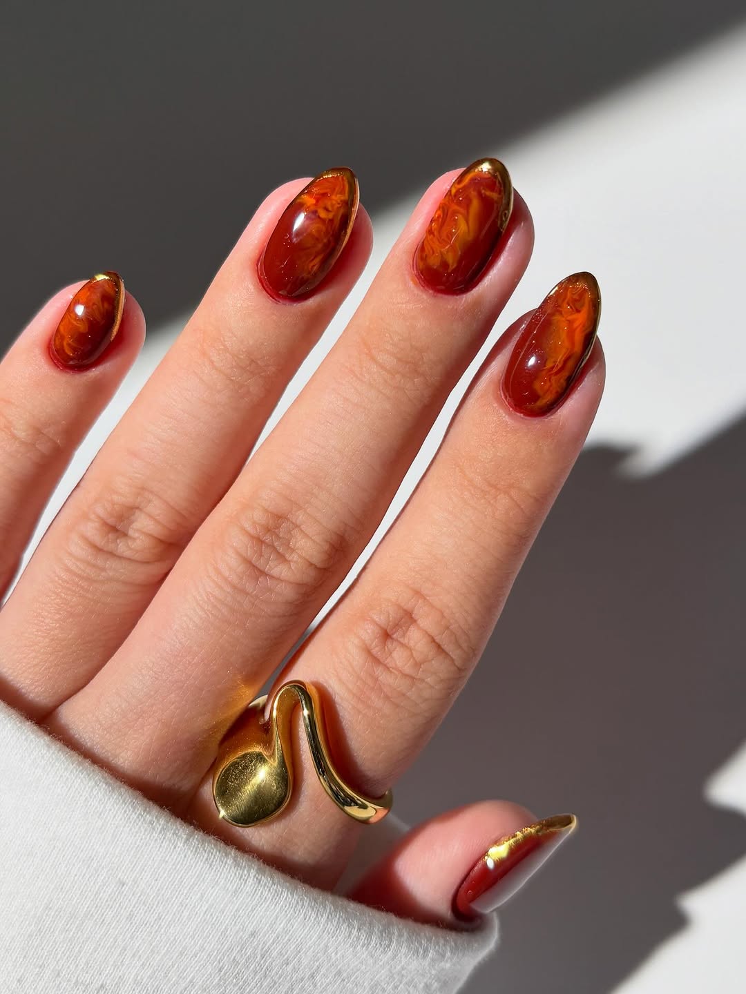 Amber and gold swirl design on almond nails.