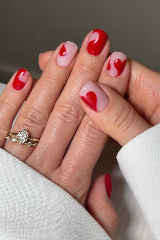 Red swirl nails with heart accents, ideal for romantic and playful styles.