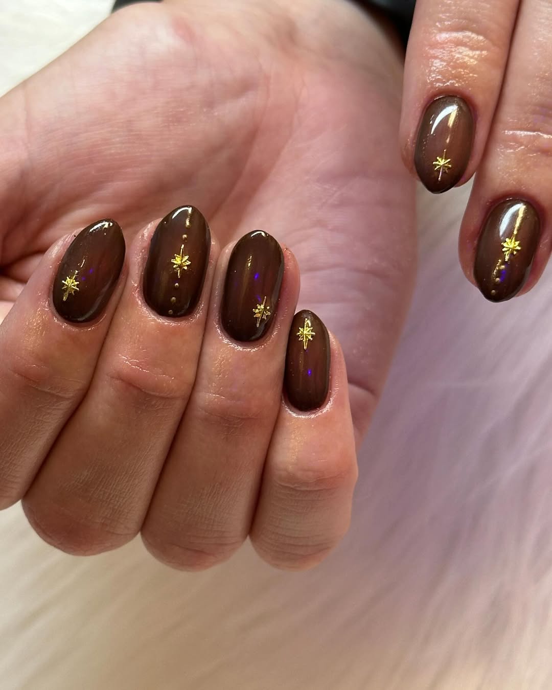 Brown nails with gold star accents, perfect for elegant and seasonal styles.