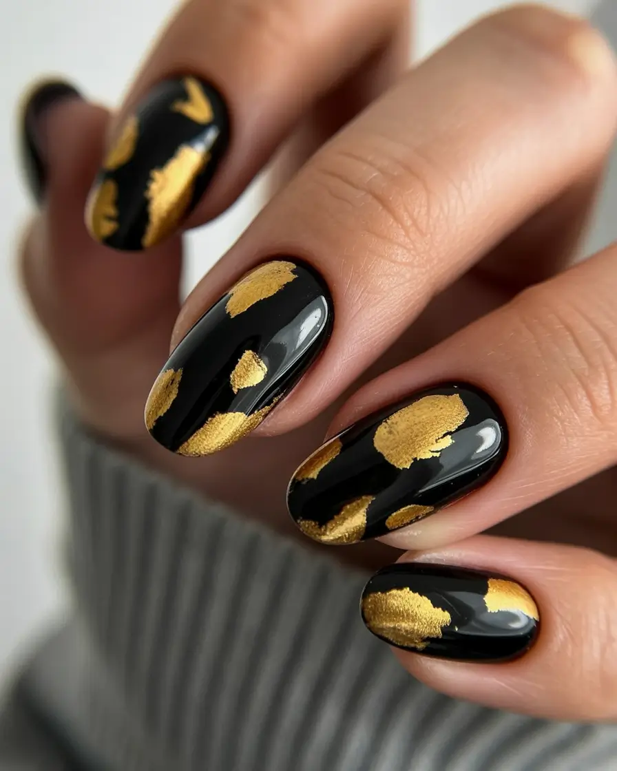 Black nails with gold foil accents for a dramatic and bold look