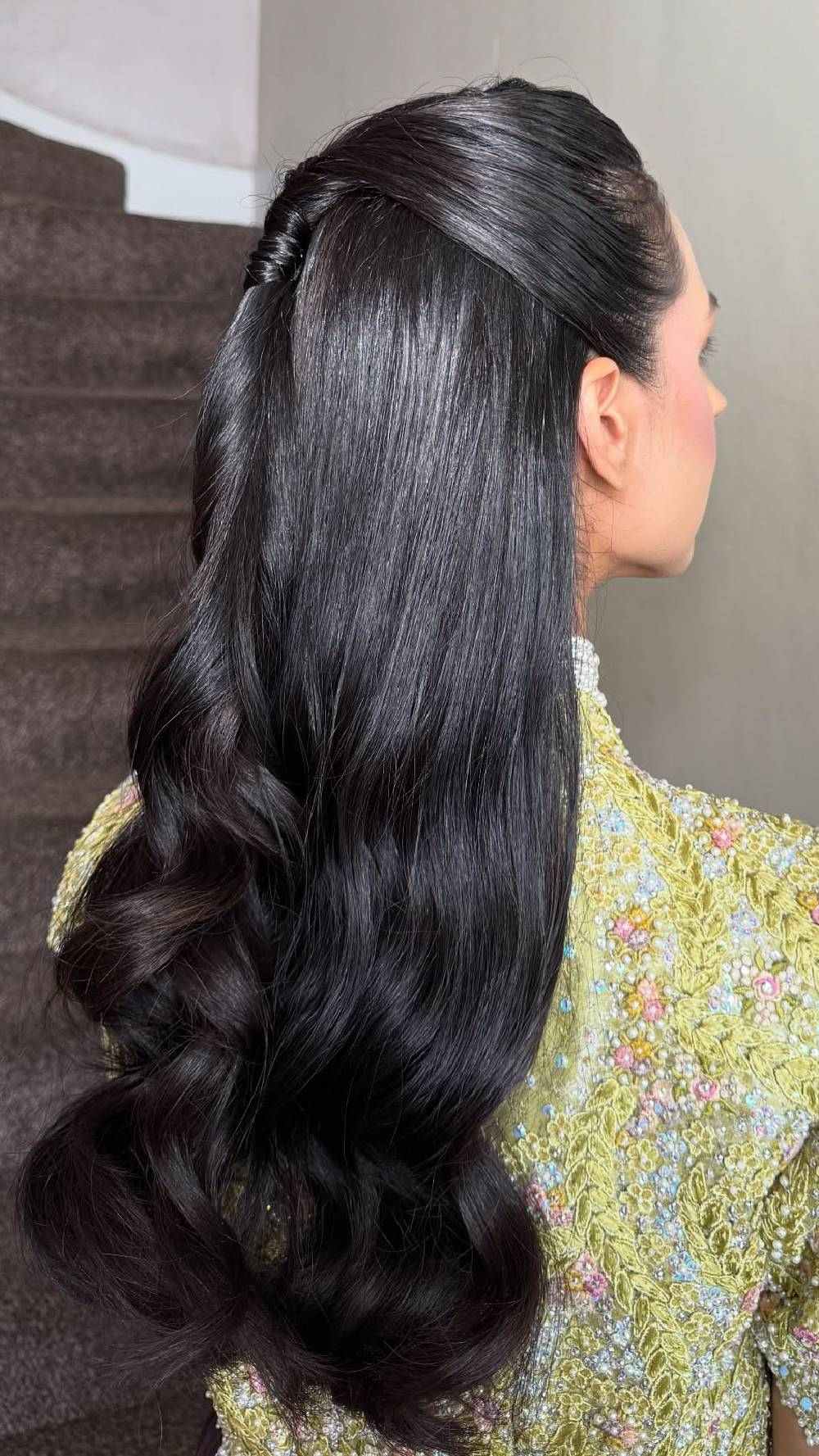 Sleek half-up hairstyle with glossy waves in black hair