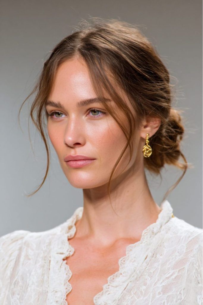 Bohemian loose bun with face-framing pieces in light brown hair