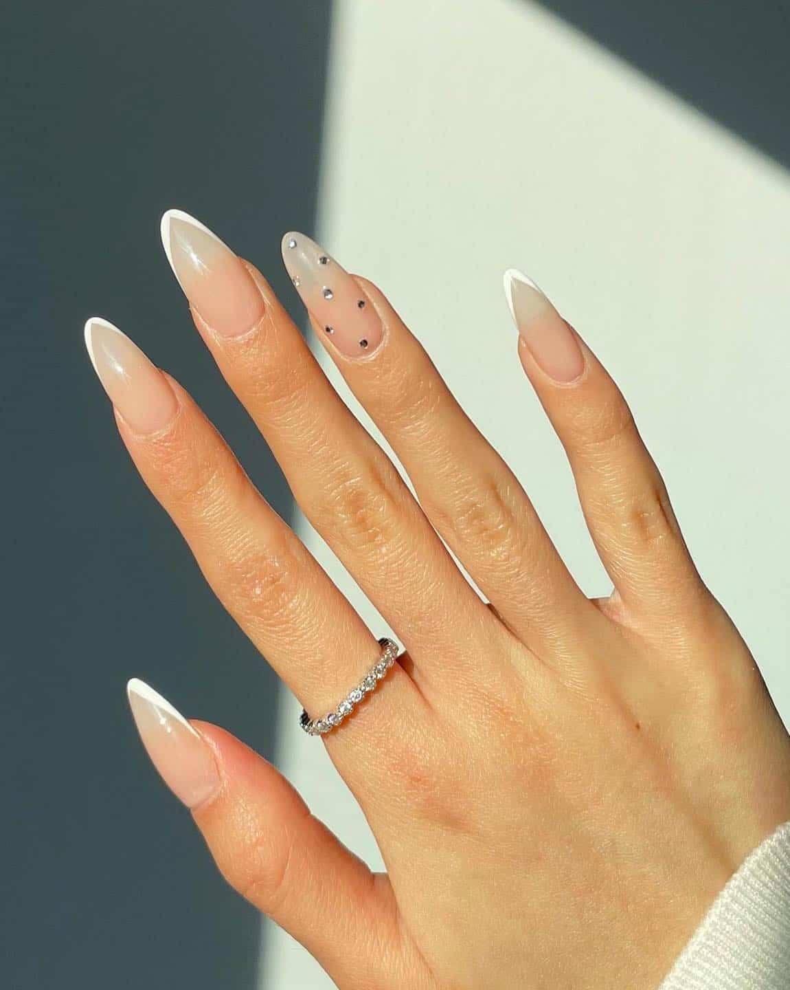 Clear almond nails with gem accents, modern and elegant