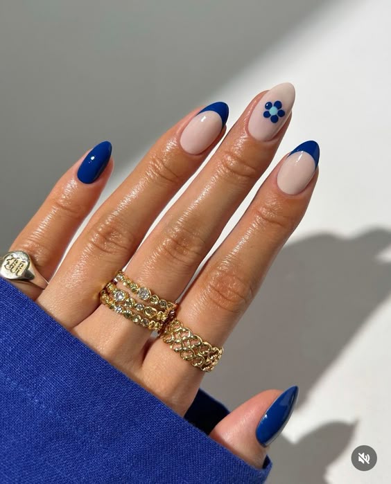 Blue French tips with floral accent on almond nails.