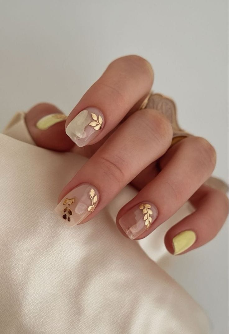 Short nails with gold botanical accents.