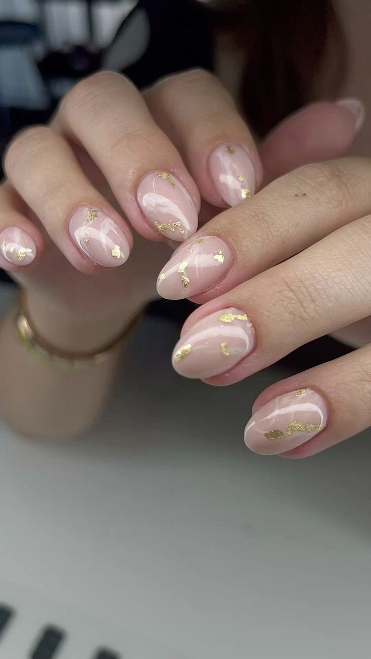 Glossy almond nails with gold leaf accents.