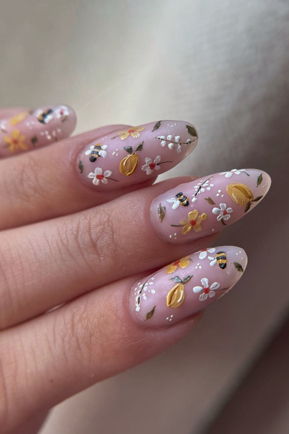 Floral almond nails with bees and petals, spring nail design