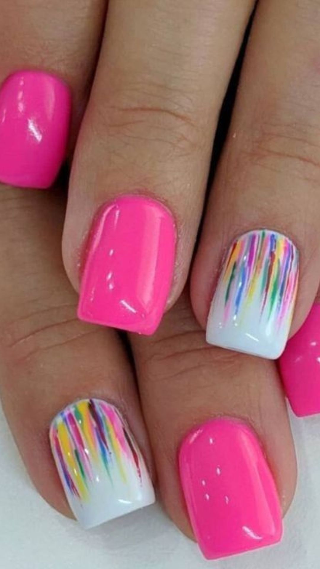 Neon pink nails with rainbow stripes, playful and vibrant.