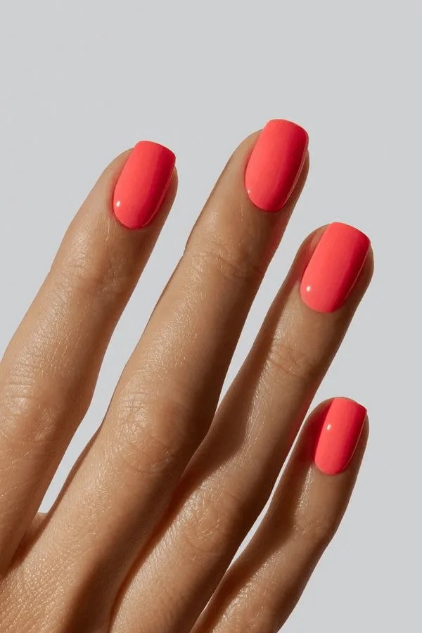 Vibrant coral nails with glossy finish.