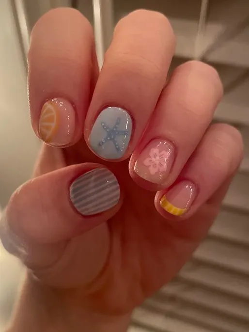 Pastel beach-themed nails with various designs.