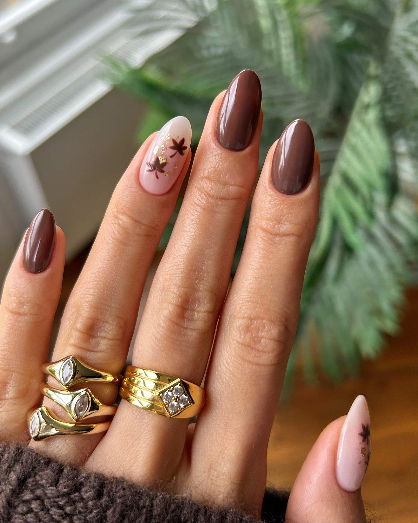 Chocolate almond nails with floral accents, chic and feminine.