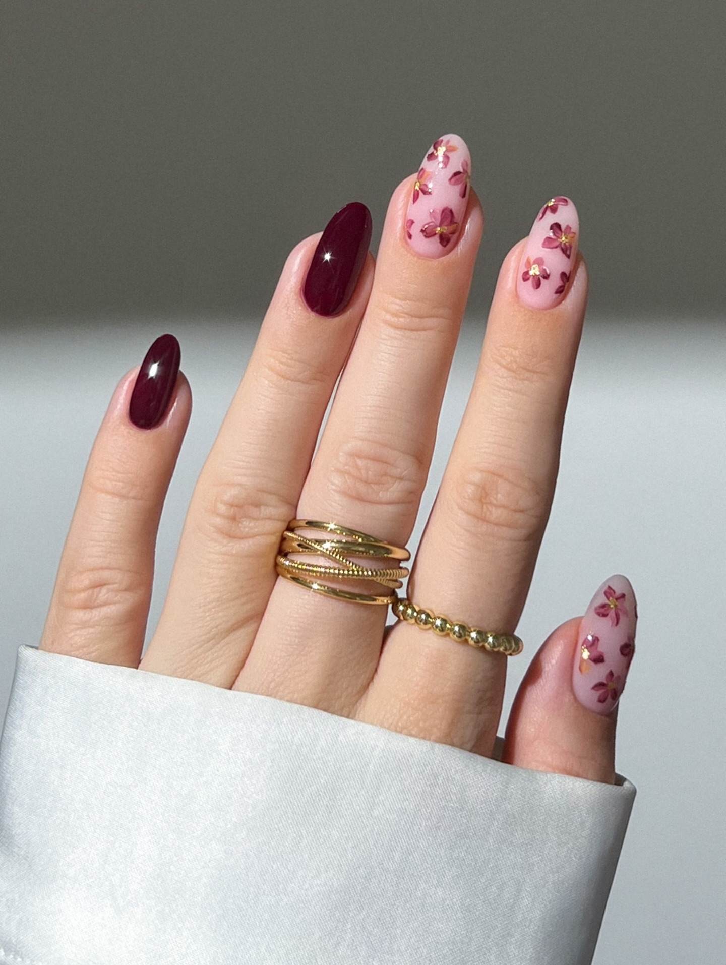 Burgundy almond nails with floral accents.