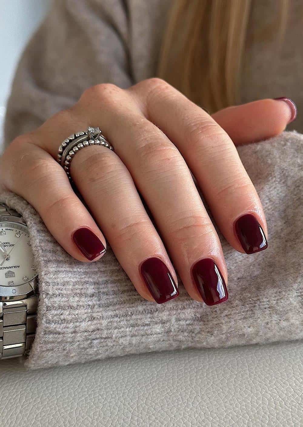 Deep burgundy short almond nails, glossy finish.