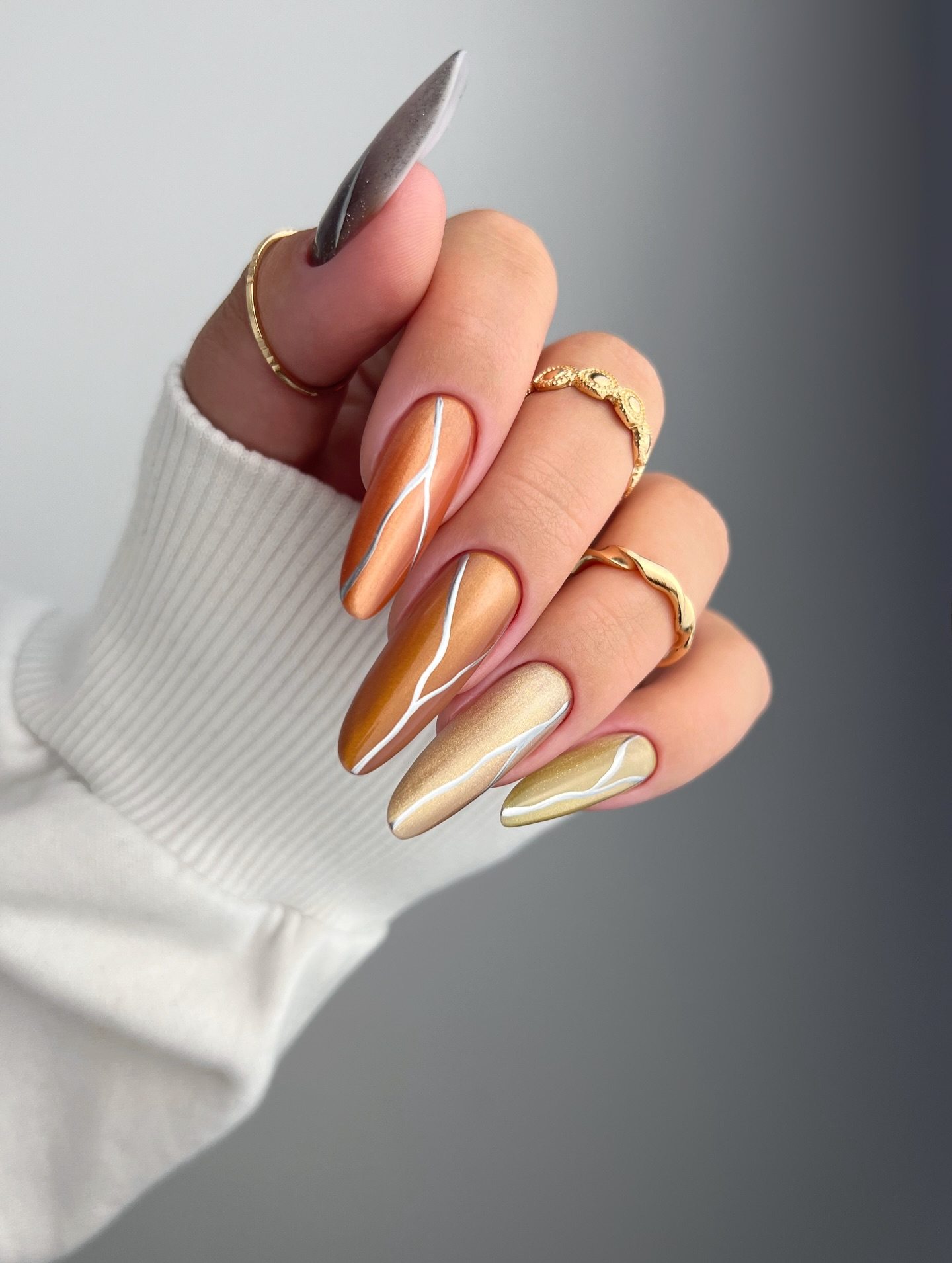 Golden almond nails, metallic and sleek.