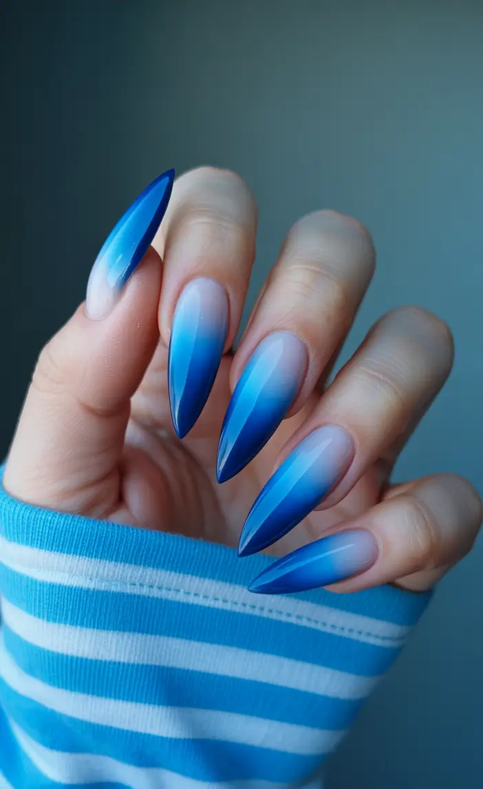 Stiletto nails with blue ombre effect, vibrant and bold.