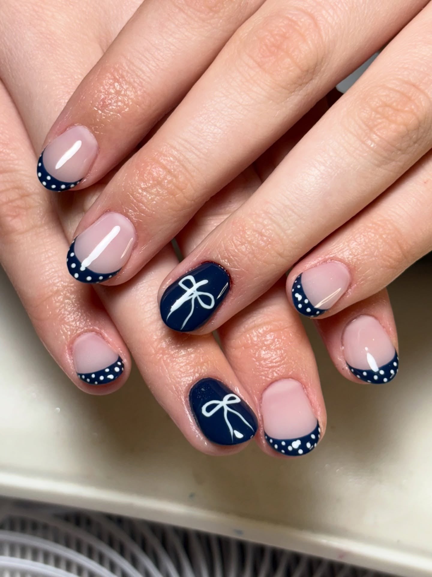 Navy French nails with polka dots, playful and stylish.
