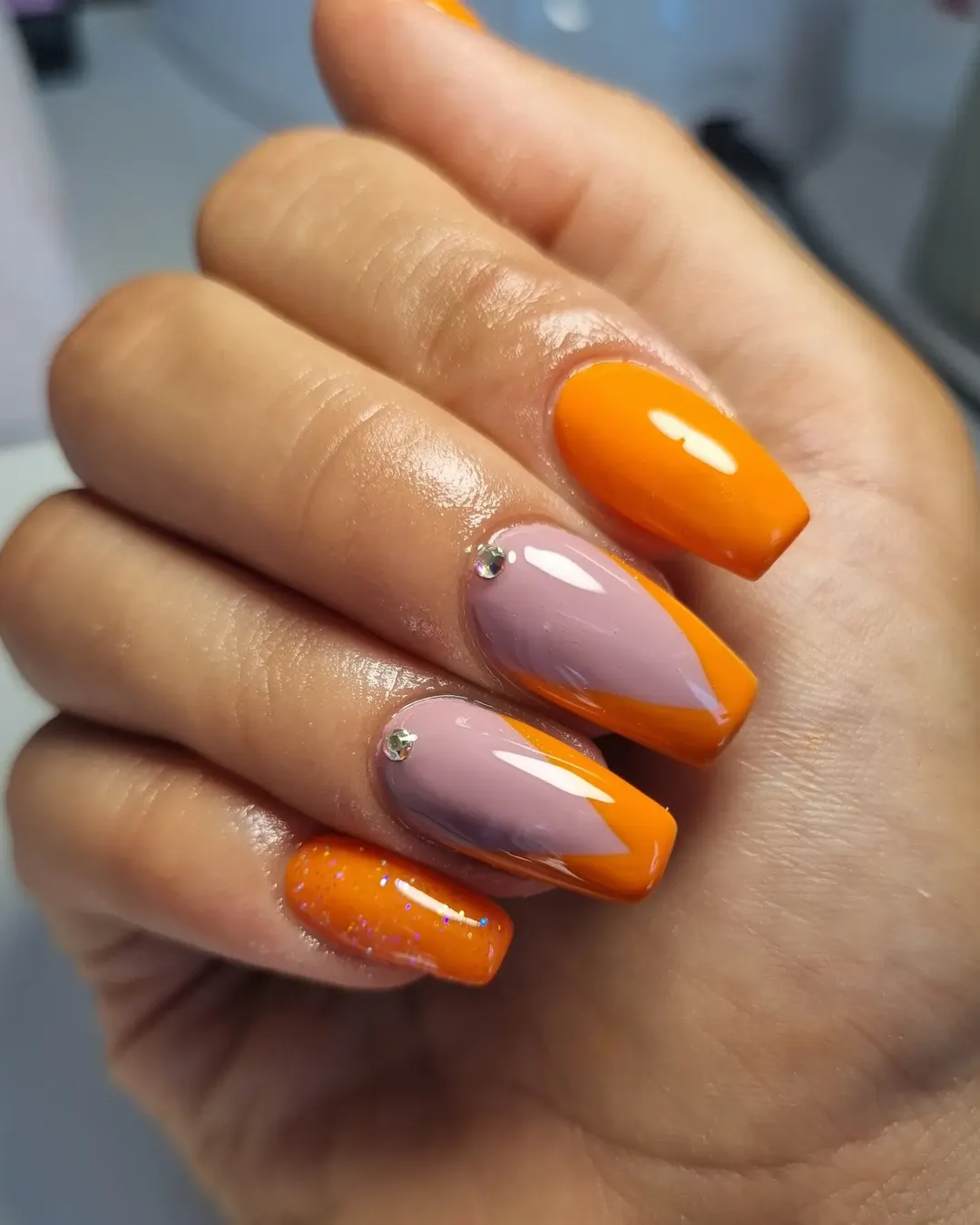 Orange and nude nails with rhinestone accents