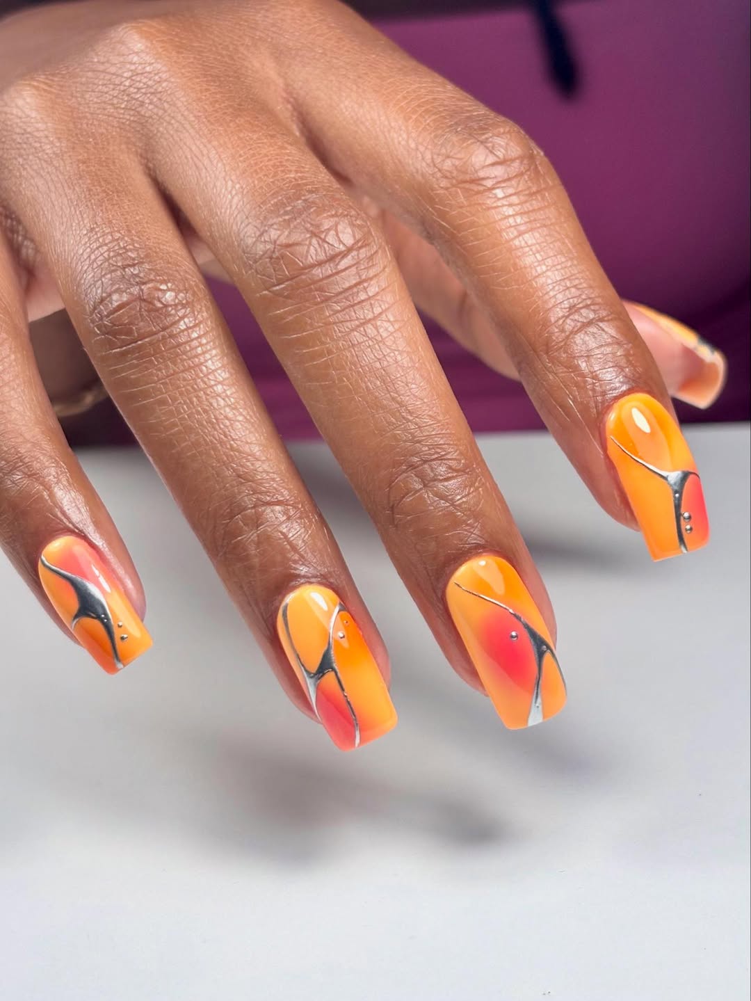 Orange nails with metallic veins design