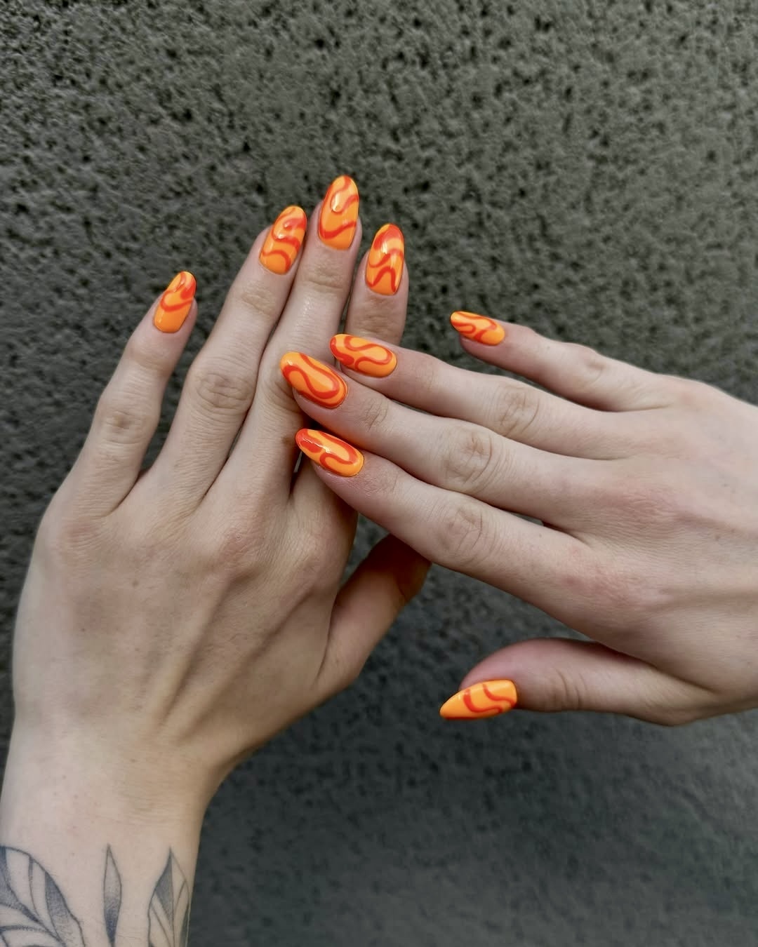 Neon orange nails with swirl design