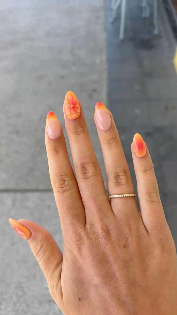 Orange ombre nails with floral accent