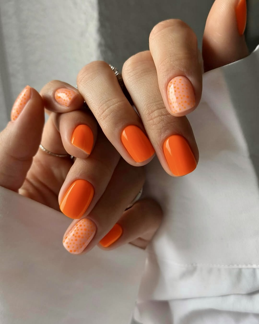 Orange nails with polka dot accent