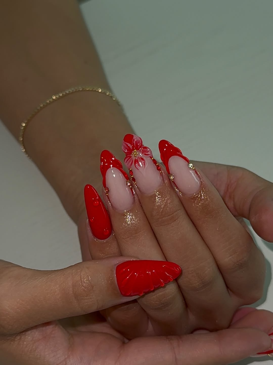 Red nails with floral accents and gold glitter